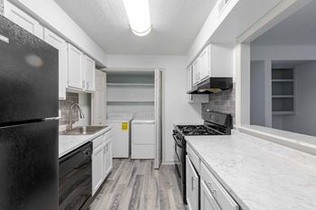 A kitchen with black appliances and white cabinets at Laurel Springs in Raleigh, NC.